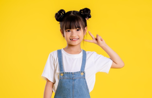 노란색 배경에 포즈를 취하는 아시아 어린 소녀의 이미지