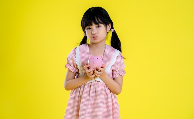 노란색 배경에 포즈를 취하는 아시아 어린 소녀의 이미지