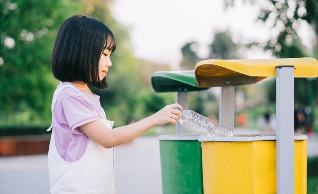 アジアの少女の画像は、使用済みペットボトルをゴミ箱に入れます