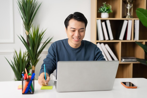 Image of Asian man sitting at home working