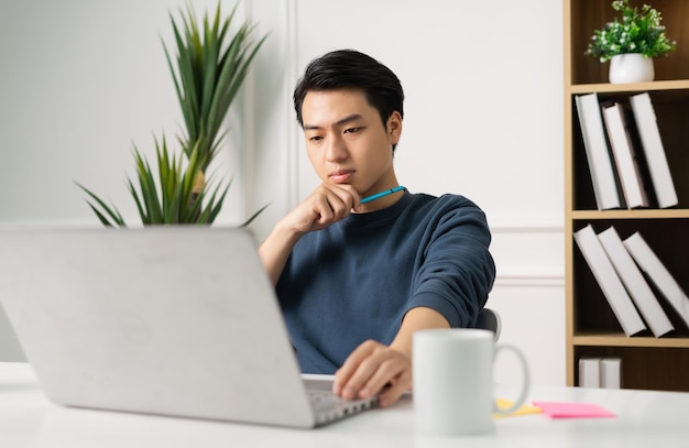 Image of Asian man sitting at home working