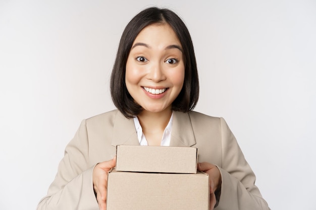 Image of asian saleswoman business woman giving boxes with order deliver to customer standing in suit over white background