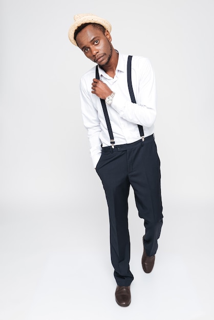 Image of attractive african man wearing hat posing in studio. Isolated over white background. Look at camera.