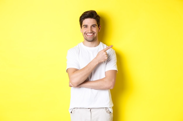 Image of attractive young man pointing finger right at copy space showing banner or promo offer stan...