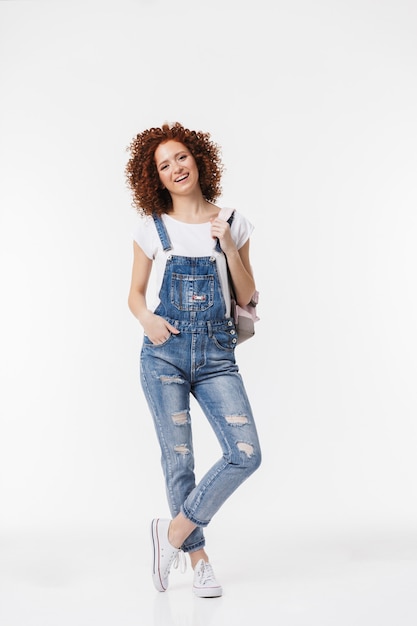 Image of a beautiful curly happy redhead girl posing isolated over white wall.