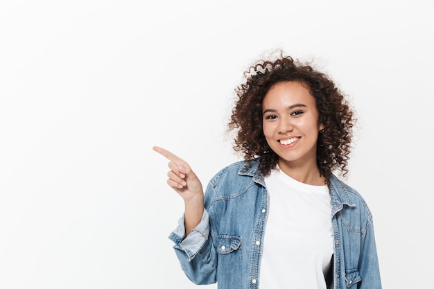 Image of a beautiful excited emotional young happy african woman posing isolated over white wall pointing.