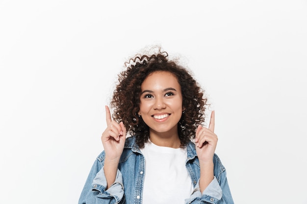 Photo image of a beautiful excited emotional young happy african woman posing isolated over white wall pointing.