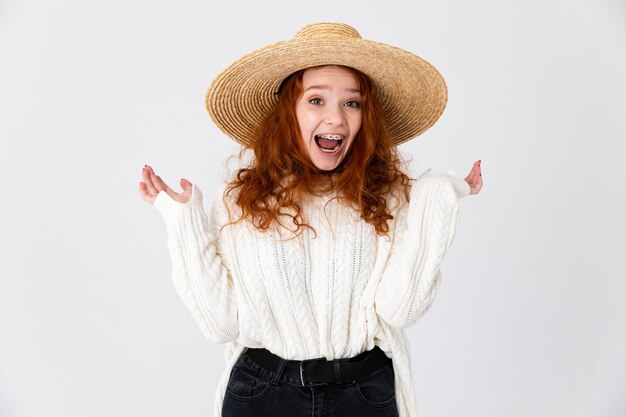 Image of a beautiful excited young cute girl redhead posing isolated over white wall background wearing hat.