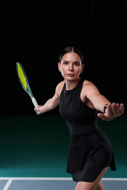 Image of a beautiful female tennis player in a black dress posing on the tennis court Sports concept