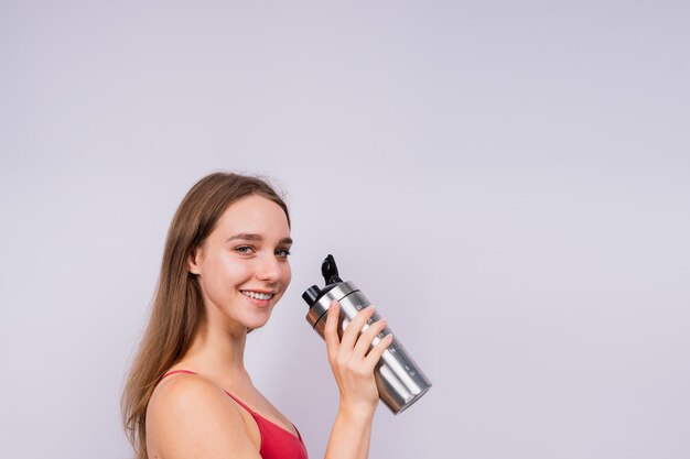 Photo image of beautiful strong happy cheerful young sports woman posing isolated indoors drinking water