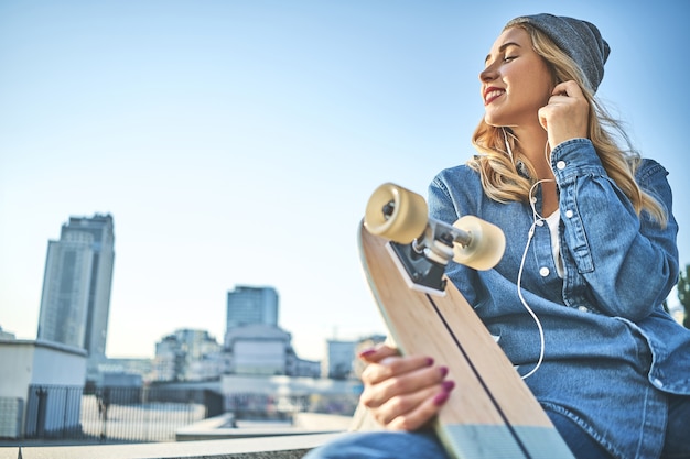 Immagine di bella donna sorridente alla moda che si siede sulle scale della strada