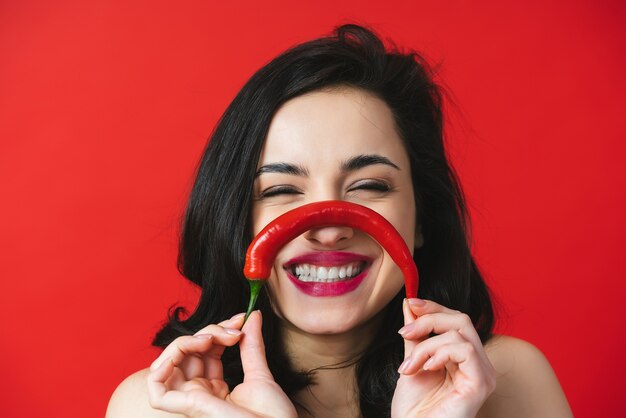 Immagine di una bella donna che si diverte con un peperoncino rosso