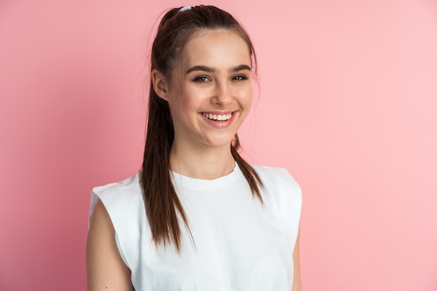 Image of beautiful woman with long hair smiling over pink background.