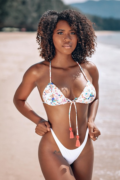 Изображение красивой молодой афроамериканки в красочных купальниках, которая стоит и позирует на камеру на пляже. Фото Бэйли Дейтон - Мисс Миссури 2017