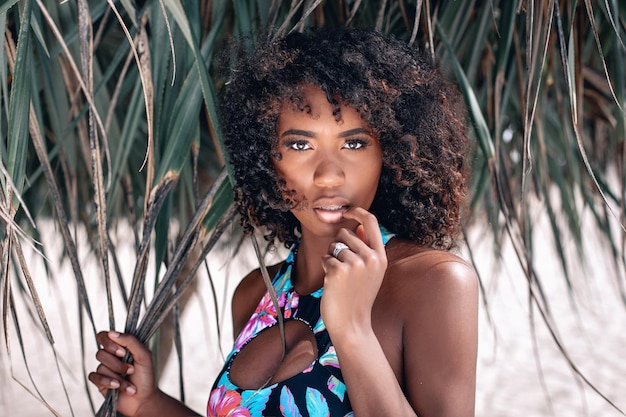 Photo image of beautiful young afro american woman in colorful swimwear staying and posing on the camera on the beach. photo of bayleigh dayton - miss missouri 2017