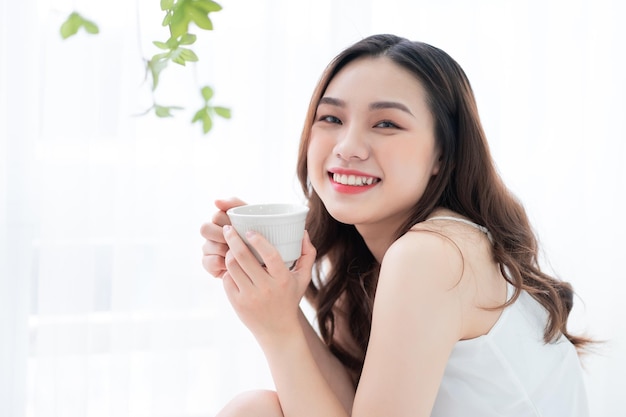 朝に家でお茶を飲む美しい若いアジアの女性の画像