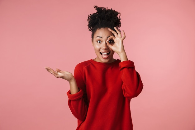 Image of a beautiful young happy african woman posing over pink wall make okay gesture.