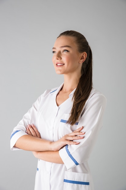 Image of a beautiful young woman cosmetologist doctor isolated over grey wall .