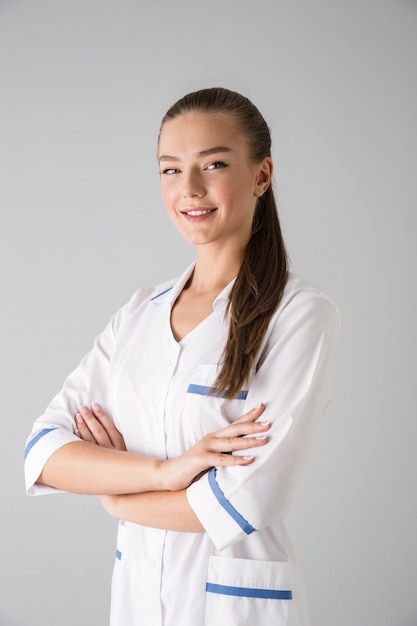 Image of a beautiful young woman cosmetologist doctor isolated over grey wall .