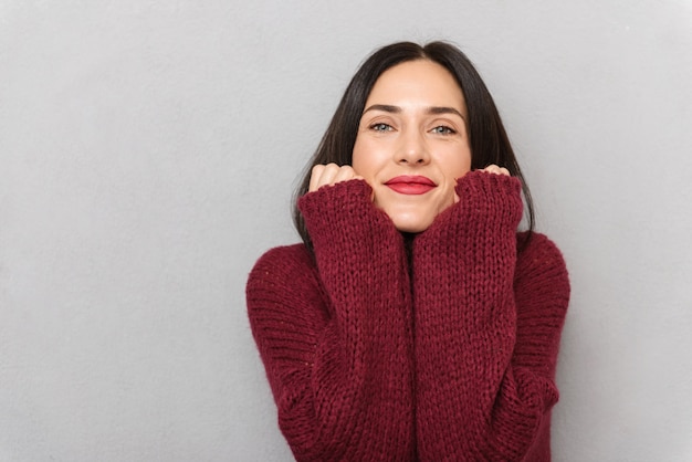 孤立したポーズのブルゴーニュのセーターに身を包んだ美しい若い女性の画像。