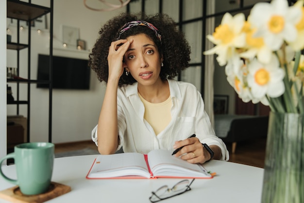 Image black woman look at camera and siting on the table at home