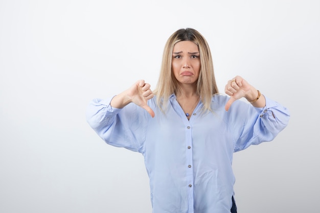 Photo image of blonde woman looking at camera on white wall.