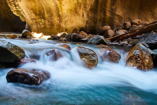 Image of Boulders with water flowing over in deep golden canyon