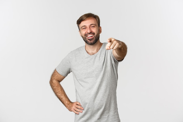 Image of carefree caucasian guy with beard, wearing gray t-shirt