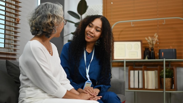 Photo image of caring female caregiver talking to senior woman elderly healthcare and home health care service concept