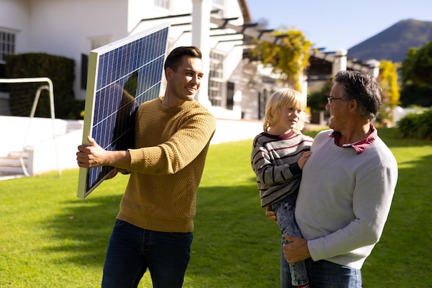 Foto immagine del padre caucasico con pannello solare, nonno e nipote. famiglia, energia verde, consapevolezza ecologica e trascorrere del tempo di qualità insieme.