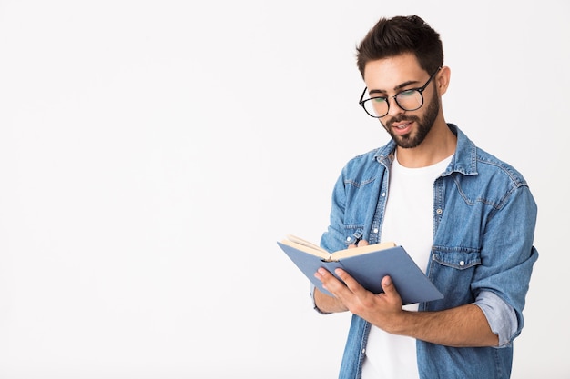 Immagine di un uomo caucasico intelligente che indossa occhiali che tiene e legge un libro isolato su un muro bianco