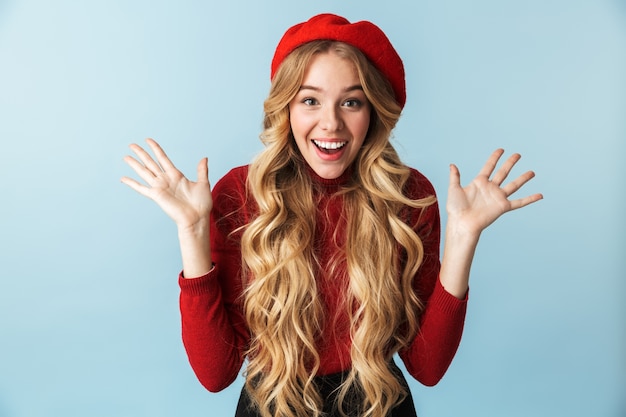 Image of charming blond woman 20s wearing red beret laughing and waving hands while standing, isolated 