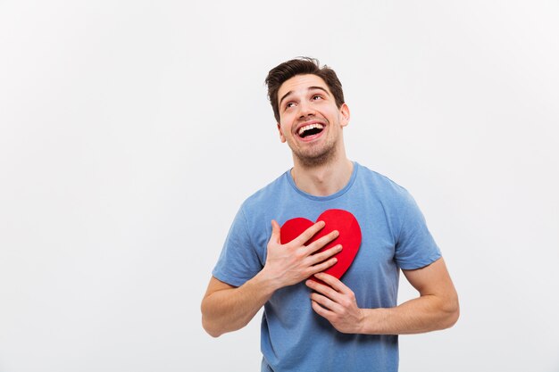 Image of Cheerful man in t-shirt hugging paper heart