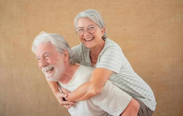 Image of cheerful senior couple having fun together while husband piggyback his wife