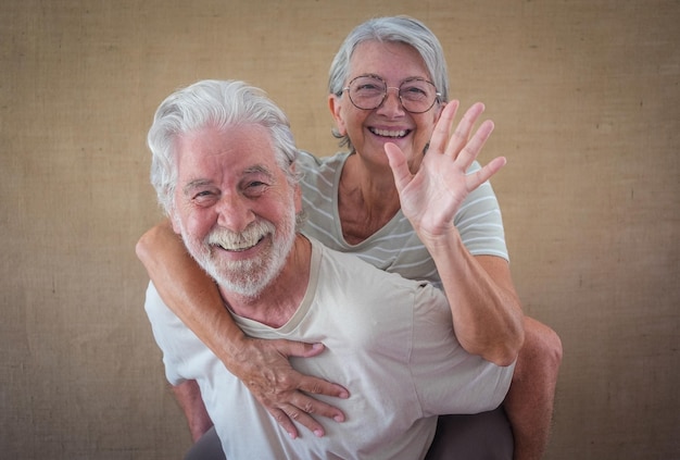 Image of cheerful senior couple having fun while man piggyback
his wife isolated over clear background