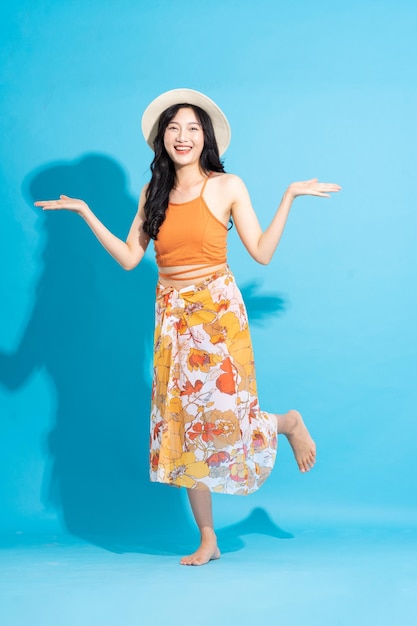 Image of cheerful smiling asian woman in swimsuit isolated on blue background