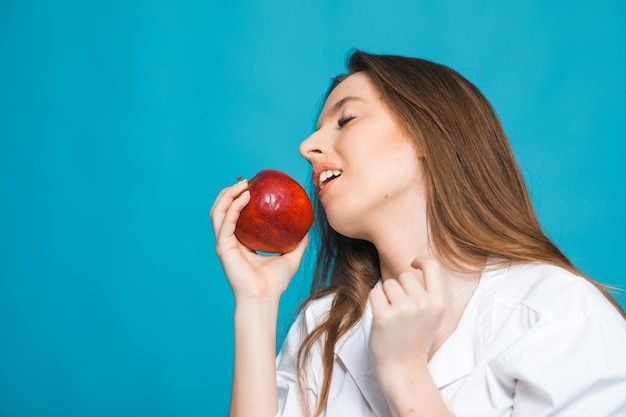 Image of a cheerful toothy young beautiful woman posing isolated over blue background holding apple