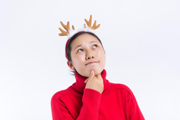 Изображение веселой молодой женщины в костюме рождественского оленя, стоящей изолированно на бордовом фоне стены и смотрящей в камеру