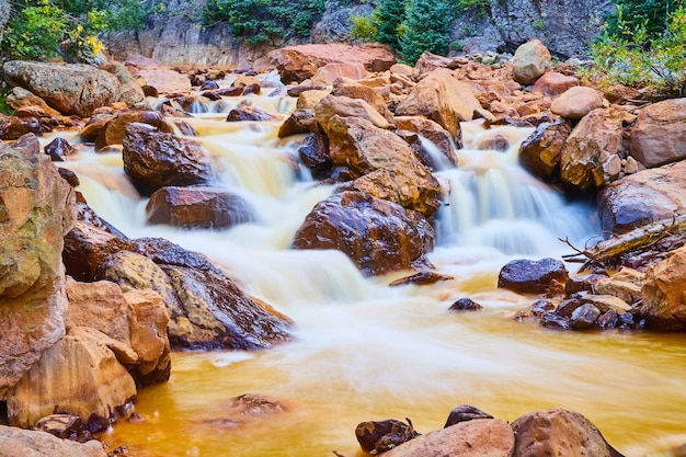 Image of Close-up of cascading waterfalls in river full of large red stones