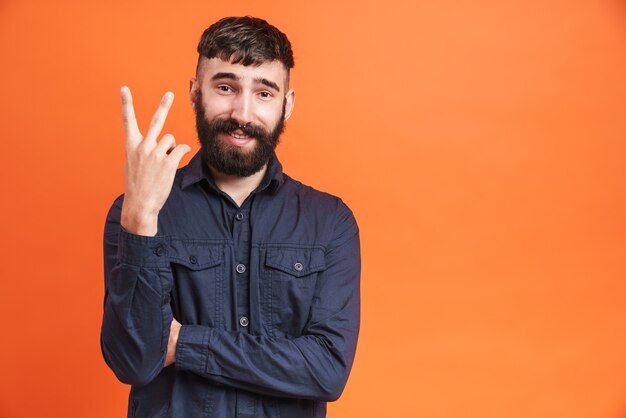 Image closeup of brunette man with nose jewelry wearing black shirt showing two fingers at camera 