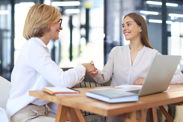 Image of collegues discussing documents and shaking hands