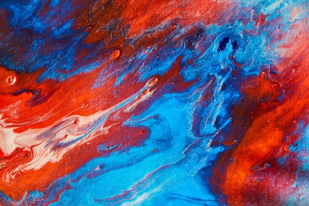 Immagine di acrilico colorato che versa su tela con rosso e blu