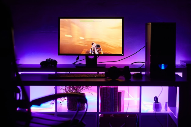 Photo image of computer monitor with game on it on the table with bright light in dark room