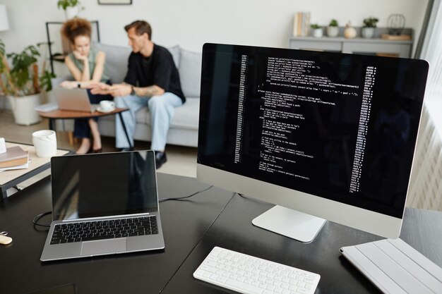 Image of computer monitor with software and laptop on the table at office