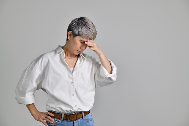 Image of confused puzzled upset middle aged Asian woman standing isolated over white background