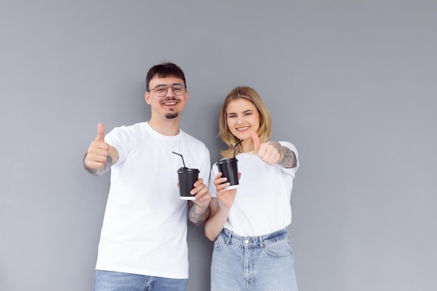 Image of content couple man and woman in denim clothes smiling while holding takeaway coffee cups