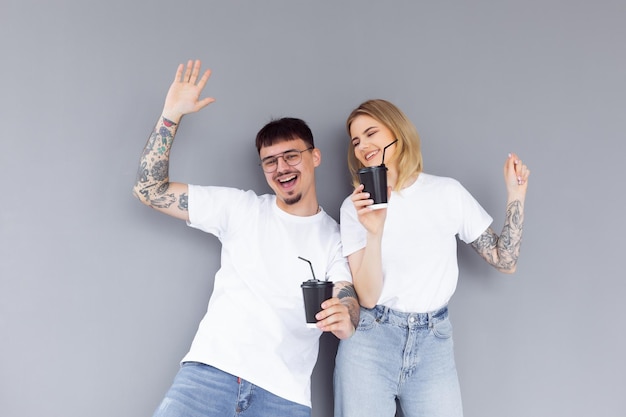 Image of content couple man and woman in denim clothes smiling while holding takeaway coffee cups