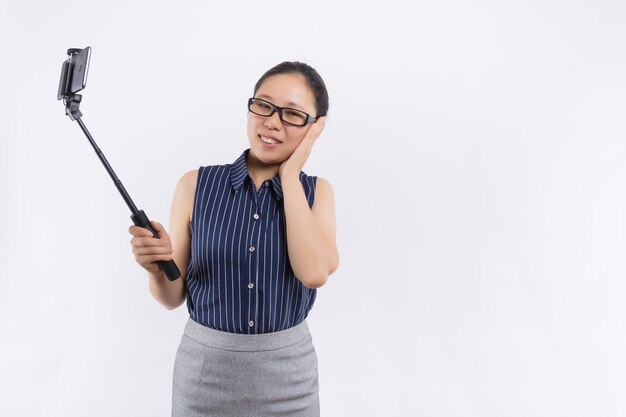 Image of cute pretty young lady isolated over blue background Looking aside make selfie by mobile phone