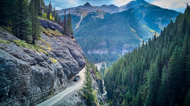 Image of Dangerous dirt road with overhanging rocks next to cliff edge in valley of mountains