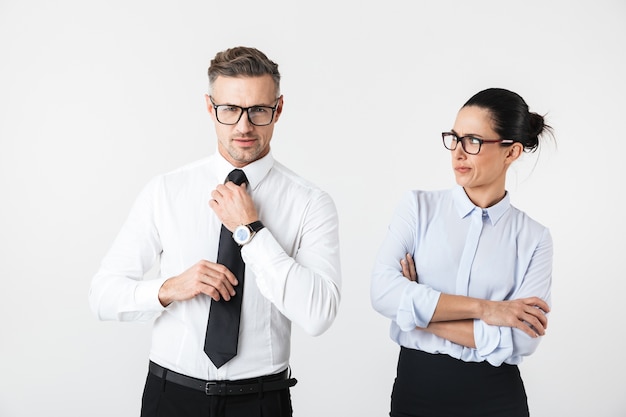 Image of displeased business woman looking at her colleague man isolated over white wall.